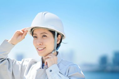 İş kıyafetleri giyen ve güzel bir günde kask takan bir kadın.