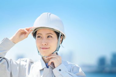 İş kıyafetleri giyen ve güzel bir günde kask takan bir kadın.