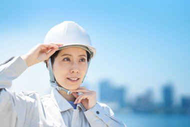 İş kıyafetleri giyen ve güzel bir günde kask takan bir kadın.