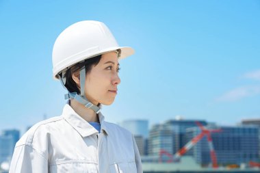 Güzel bir günde kask takan ve iş kıyafeti giyen bir kadın.