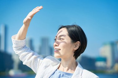 A woman blocking the strong sunlight with her hand on fine day