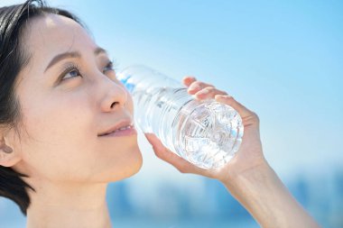 Dışarıdaki plastik şişeden su içen kadın.