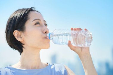 Dışarıdaki plastik şişeden su içen kadın.