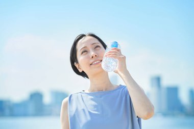 Dışarıdaki plastik şişeden su içen kadın.