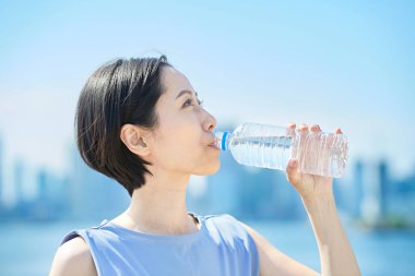 Dışarıdaki plastik şişeden su içen kadın.