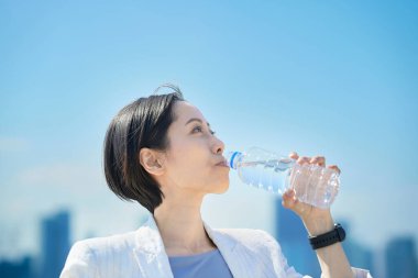 Dışarıdaki plastik şişeden su içen kadın.
