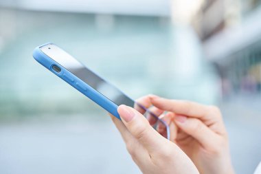 Sokak köşesinde akıllı telefon kullanan bir kadının eli.