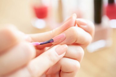 Bir kadının eli parmağına oje sürüyor.