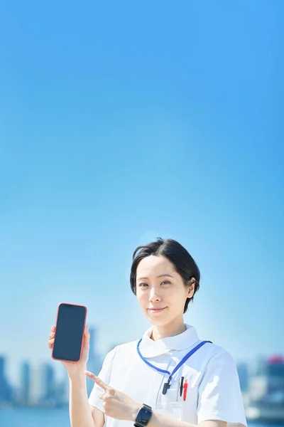 Beyaz Önlüklü Bir Kadın Dışarıda Akıllı Telefon Tutuyor — Stok fotoğraf