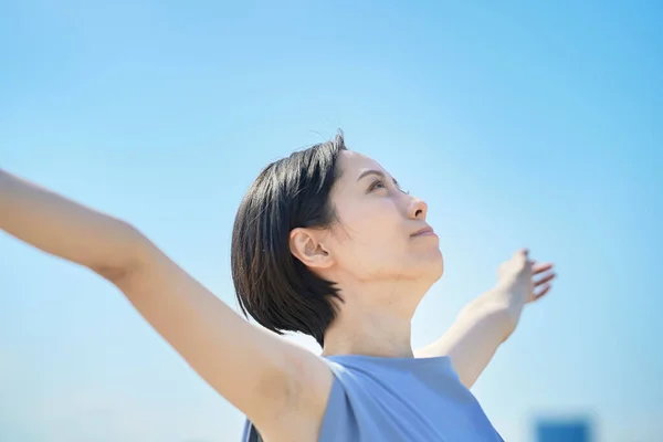 stock image A woman with a relaxed expression under the blue sky in city