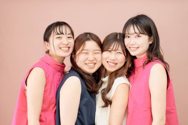 Renkli bir arka planın önünde duran dört genç kadından oluşan bir grup.