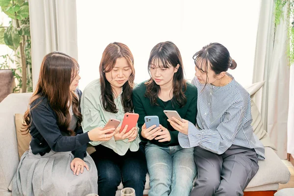 Dört Kadın Içeride Akıllı Telefonlarına Bakarken Konuşuyor — Stok fotoğraf