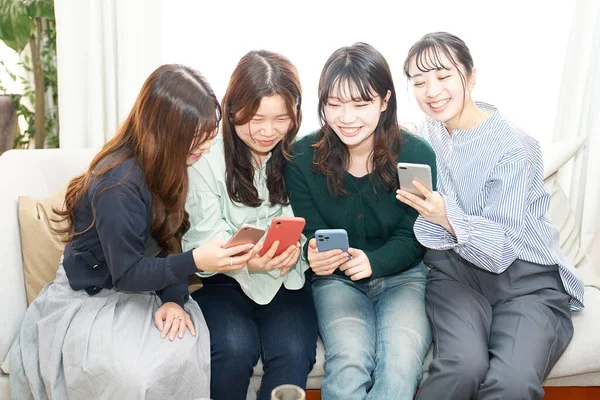 Dört Kadın Içeride Akıllı Telefonlarına Bakarken Konuşuyor — Stok fotoğraf