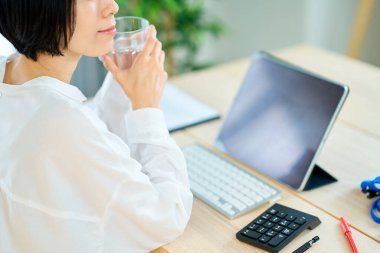 Odasında bilgisayarla uğraşırken mola veren bir kadın.