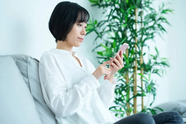 Žena Sedí Pohovce Používá Smartphone Místnosti — Stock fotografie