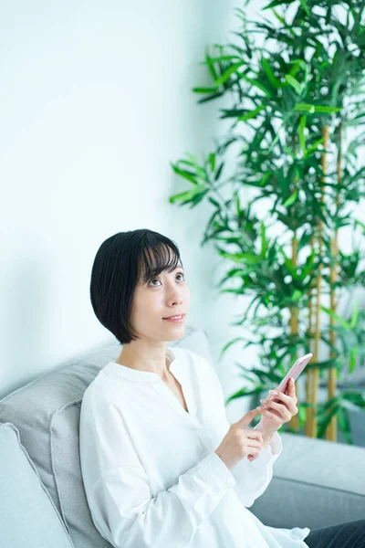 Kobieta Siedząca Kanapie Korzystająca Smartfona Pokoju — Zdjęcie stockowe