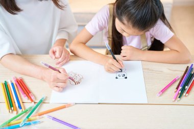 Ebeveyn ve çocuk odada oynuyor ve resim çiziyor.