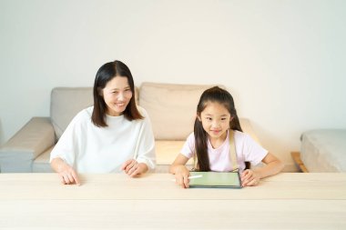 Ebeveyn ve çocuk odada tabletle oynuyorlar.