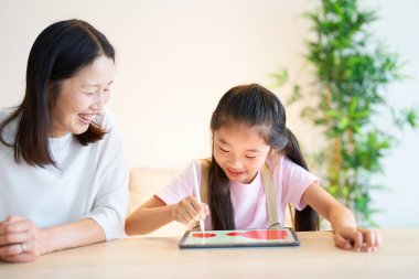 Ebeveyn ve çocuk odada tabletle oynuyorlar.