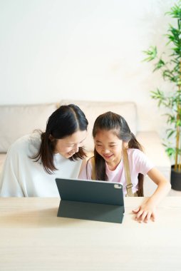 Tablet ekranına gülümseyerek bakan ebeveyn ve çocuk