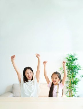 İki elini de seve seve kaldıran ebeveyn ve çocuk.