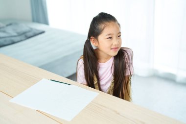 Not defterini açıp öğretmeni dinleyen bir kız.