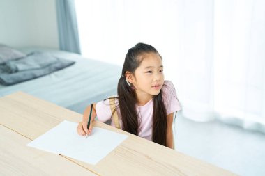 Not defterini açıp öğretmeni dinleyen bir kız.