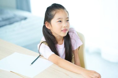 Not defterini açıp öğretmeni dinleyen bir kız.