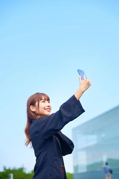 Mujer Joven Sosteniendo Teléfono Inteligente Bajo Cielo Azul — Foto de Stock