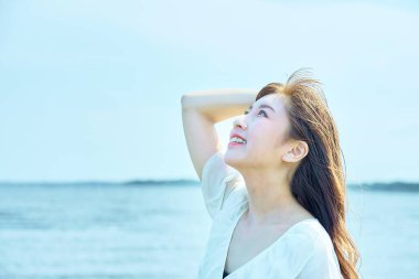 Güzel bir günde sahilde yürüyen bir kadın.