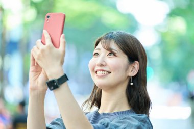 Dışarıda akıllı telefon tutan genç bir kadın.