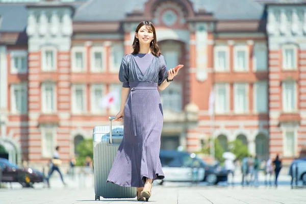 晴れた日にスーツケースを持って街を歩く女性 — ストック写真