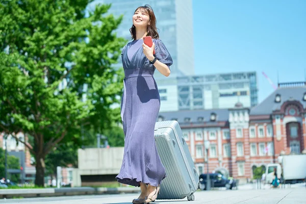 晴れた日にスーツケースを持って街を歩く女性 — ストック写真