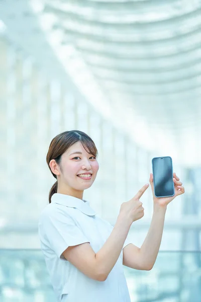 Beyaz Önlüklü Bir Kadın Elinde Dijital Bir Cihaz Tutuyor — Stok fotoğraf