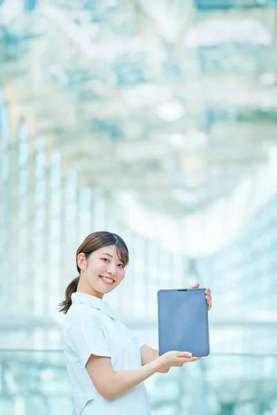 Una Mujer Con Una Bata Blanca Sosteniendo Dispositivo Digital Interior — Foto de Stock
