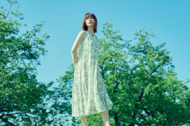 Yeşil bir alanda rahat bir ifadeyle yürüyen genç bir kadın.