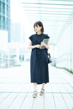 Genç iş kadını gündelik kıyafetlerle yürüyor.