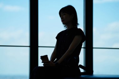 Bir gözlemevinden manzaraya bakan genç bir kadının silueti.