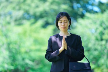 Ellerini açık havada yas elbisesi içinde birleştiren bir kadın.