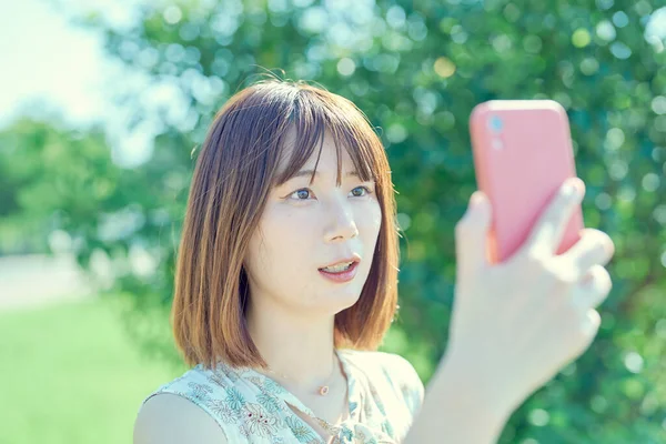 Ung Kvinna Hålla Och Titta Smartphone Utomhus — Stockfoto