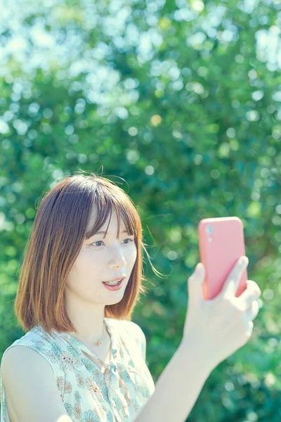 Ung Kvinna Hålla Och Titta Smartphone Utomhus — Stockfoto