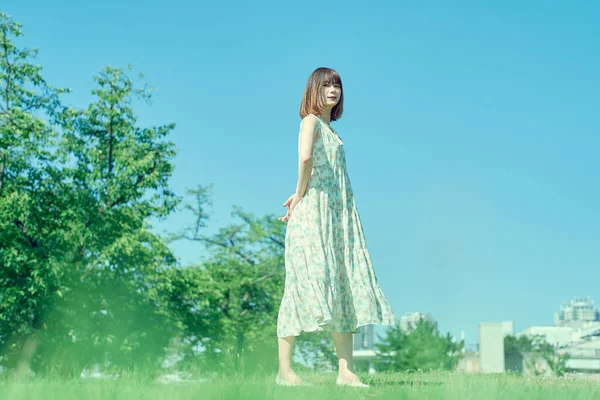 ゆったりとした表情で緑の空間を歩く若い女性 — ストック写真
