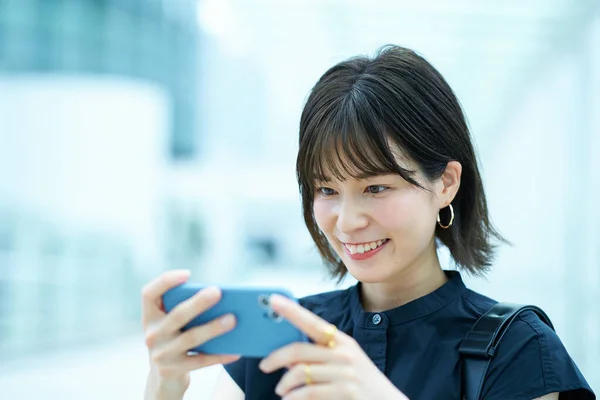 屋外でスマートフォン画面を見ている若い女性 — ストック写真