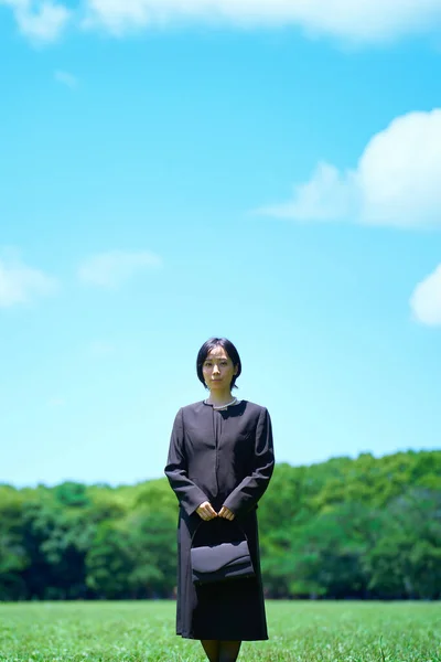 A woman in mourning clothes standing in a green space