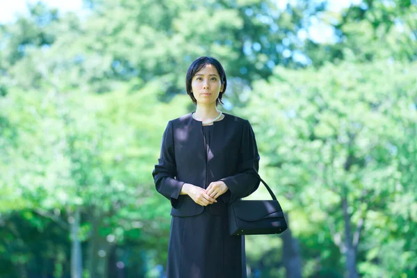 A woman in mourning clothes standing in a green space