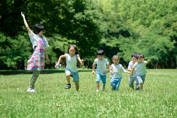 Bambini Che Corrono Una Donna Che Guarda Nel Parco — Foto Stock