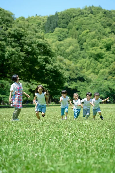 Bambini Che Corrono Una Donna Che Guarda Nel Parco — Foto Stock