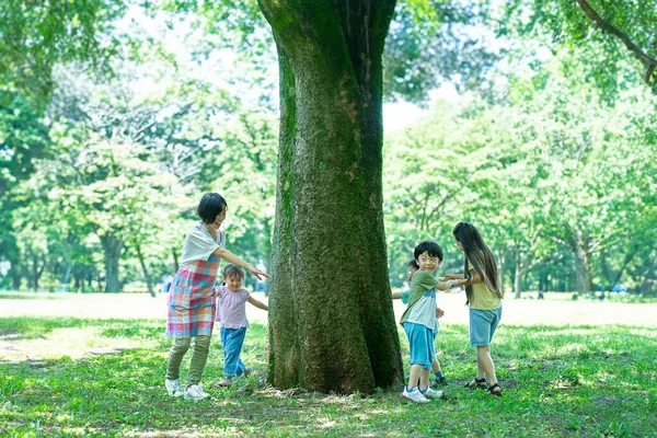 儿童和妇女牵着手 绕着公园里的树走着 — 图库照片