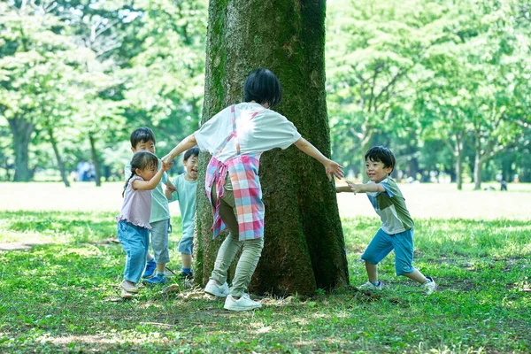 子供と女性が手を握り 公園の木の周りを回って — ストック写真