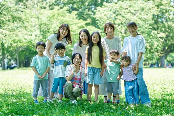 Group photo of children, parents and a female teacher in the park